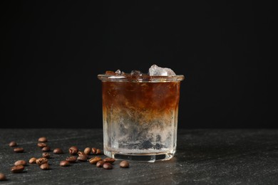 Photo of Refreshing espresso tonic drink and coffee beans on dark table