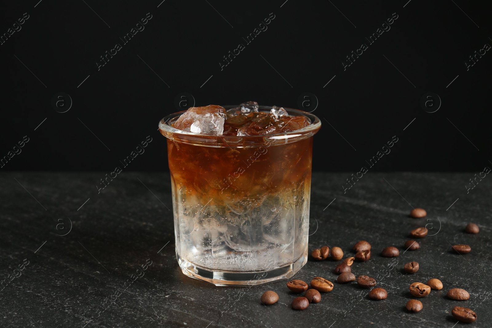 Photo of Refreshing espresso tonic drink and coffee beans on dark table