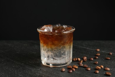 Photo of Refreshing espresso tonic drink and coffee beans on dark table