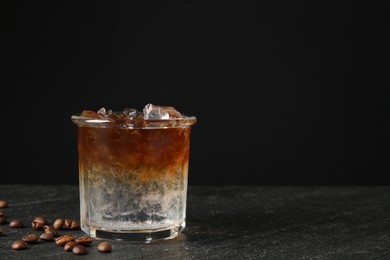 Refreshing espresso tonic drink and coffee beans on dark table. Space for text