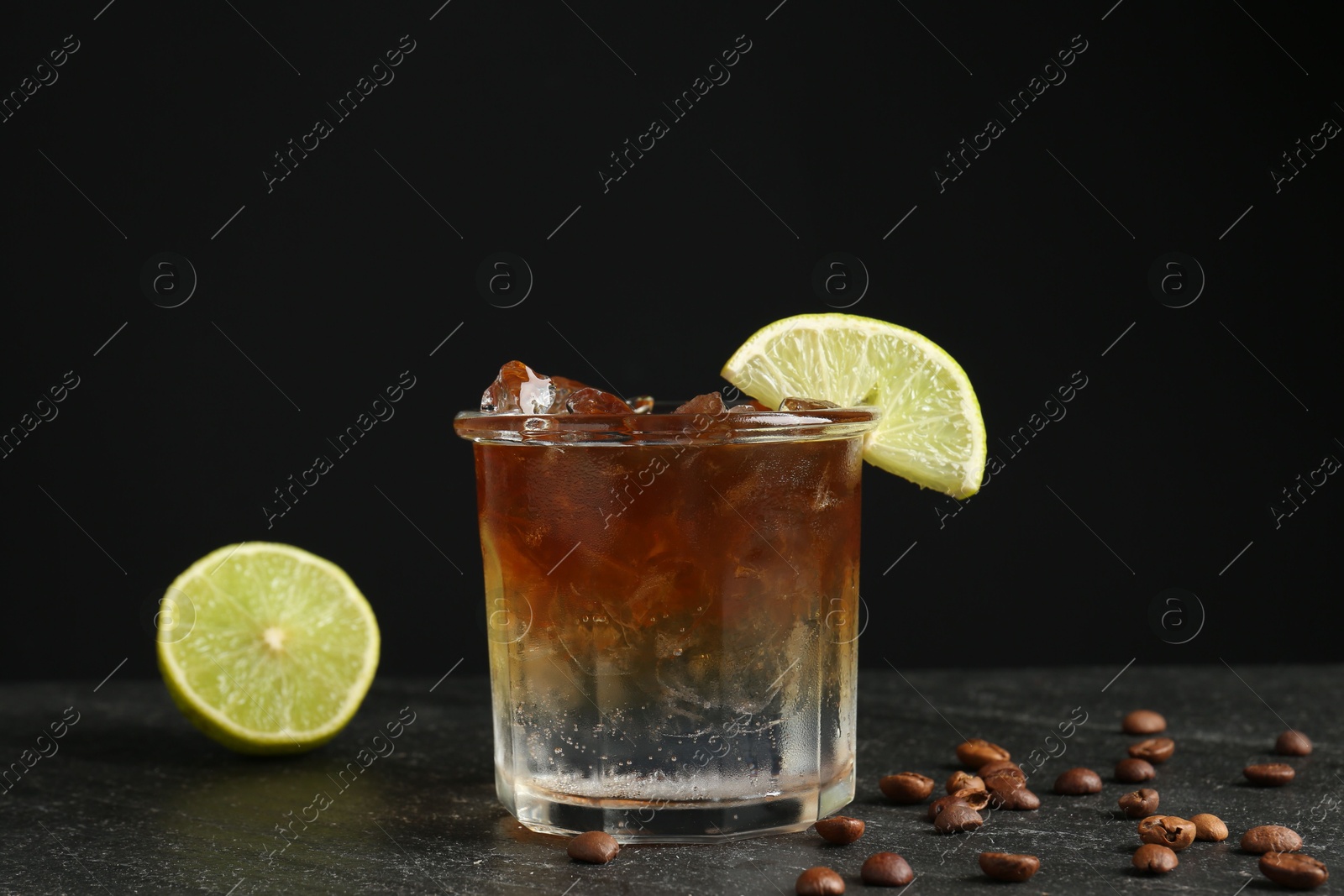 Photo of Refreshing espresso tonic drink with slice of lime and coffee beans on dark table