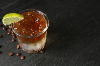 Photo of Refreshing espresso tonic drink with slice of lime and coffee beans on dark table, closeup. Space for text