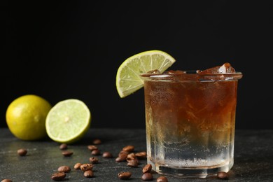 Photo of Refreshing espresso tonic drink with slice of lime and coffee beans on dark table, closeup