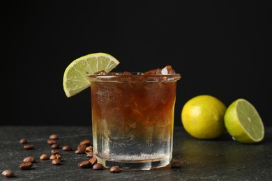 Photo of Refreshing espresso tonic drink with slice of lime and coffee beans on dark table, closeup