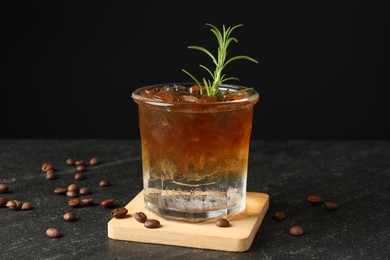 Photo of Refreshing espresso tonic drink with rosemary and coffee beans on dark table