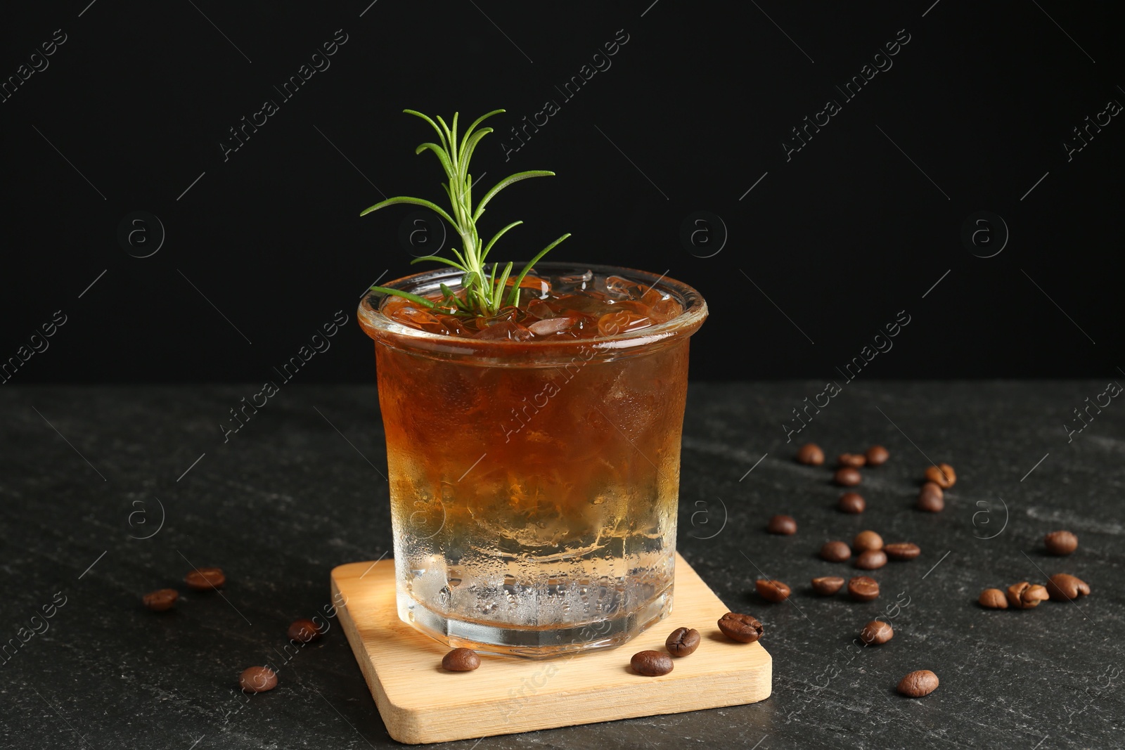 Photo of Refreshing espresso tonic drink with rosemary and coffee beans on dark table