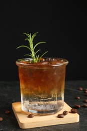 Photo of Refreshing espresso tonic drink with rosemary and coffee beans on dark table