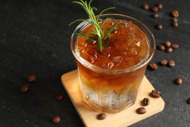 Photo of Refreshing espresso tonic drink with rosemary and coffee beans on dark table, closeup