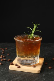 Photo of Refreshing espresso tonic drink with rosemary and coffee beans on dark table