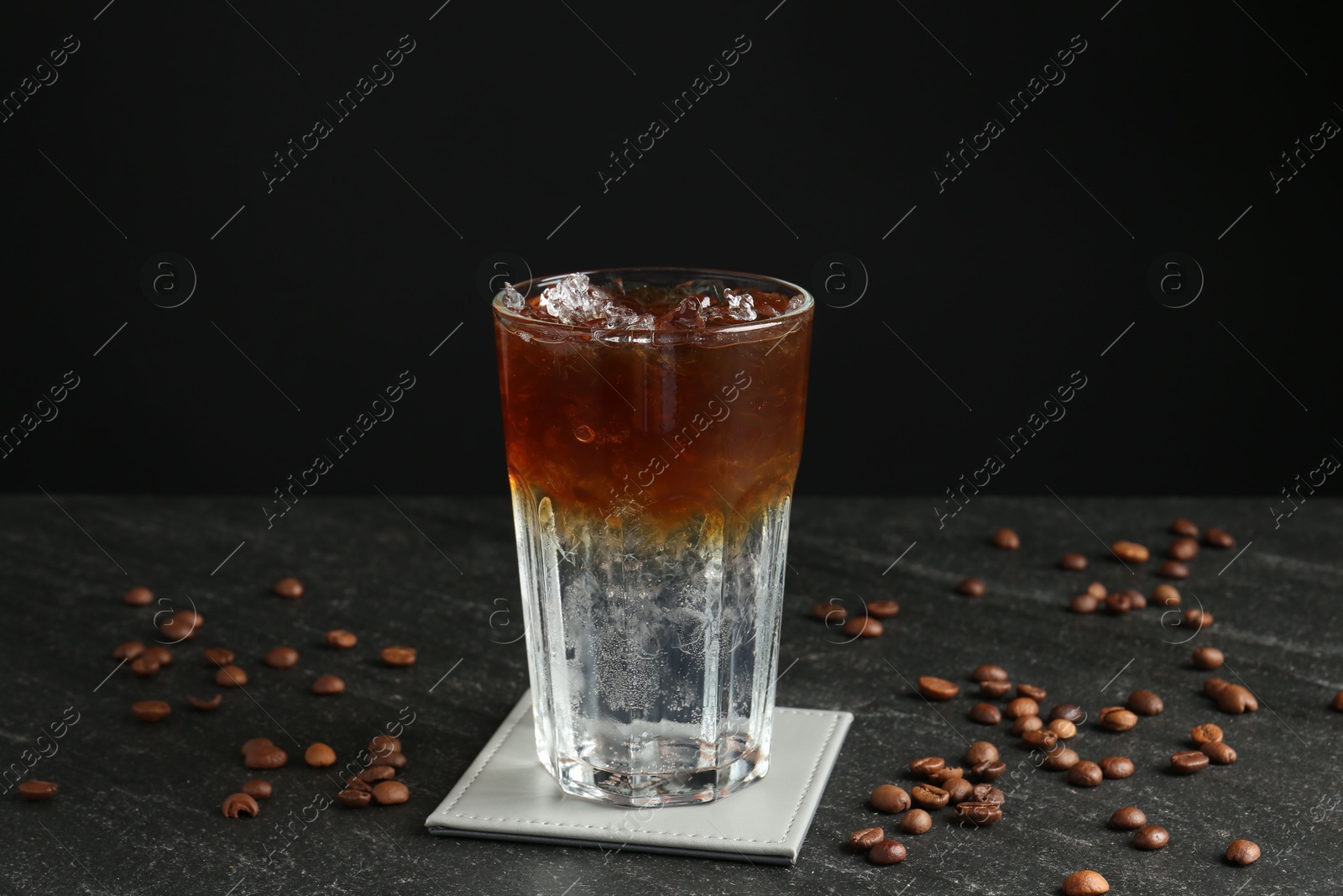 Photo of Refreshing espresso tonic drink and coffee beans on dark table