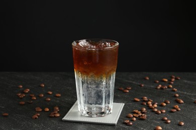 Photo of Refreshing espresso tonic drink and coffee beans on dark table