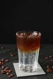 Photo of Refreshing espresso tonic drink and coffee beans on dark table