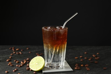 Photo of Refreshing espresso tonic drink with slice of lime and coffee beans on dark table