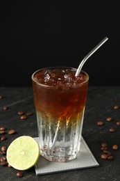 Photo of Refreshing espresso tonic drink with slice of lime and coffee beans on dark table