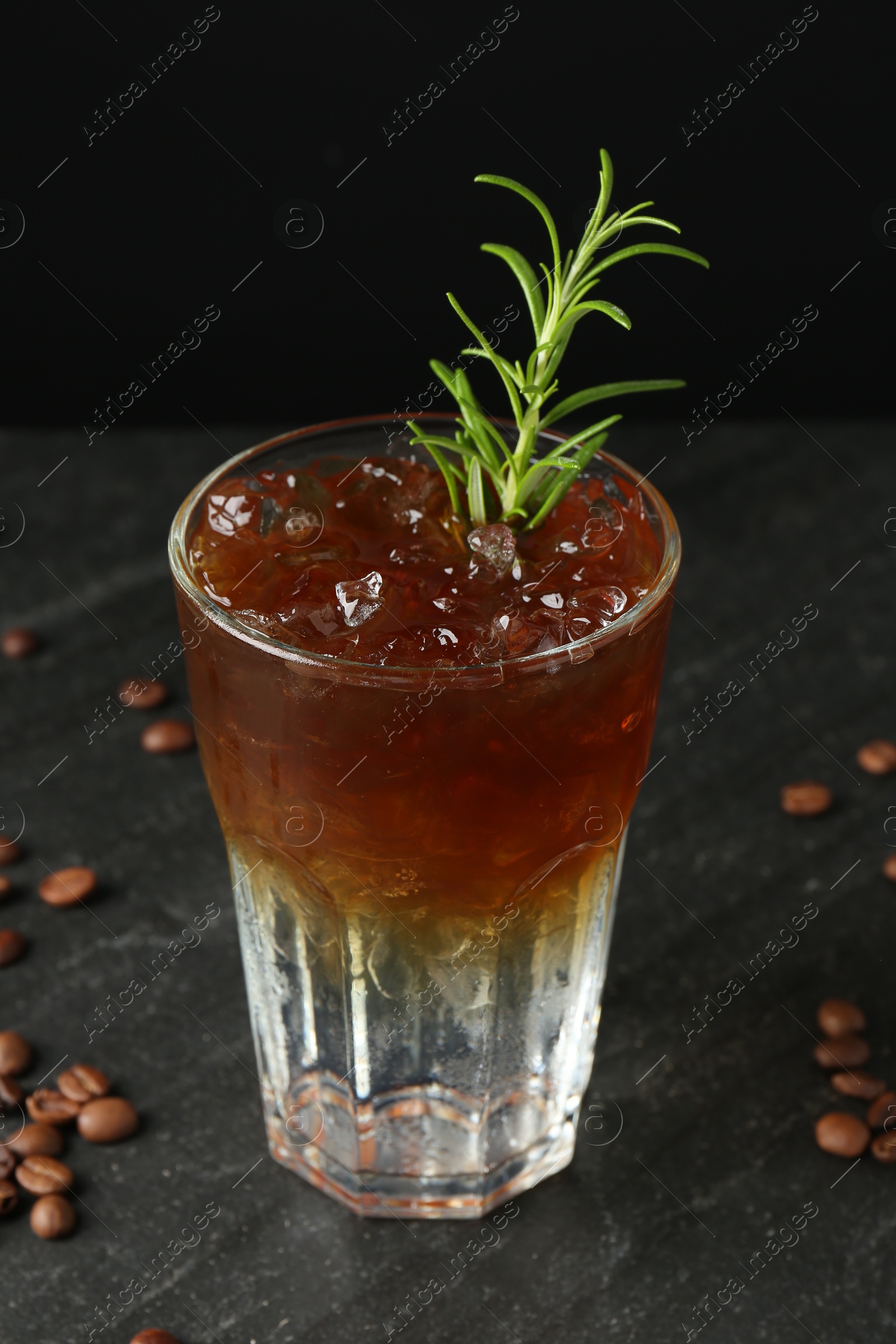 Photo of Refreshing espresso tonic drink with rosemary and coffee beans on dark table