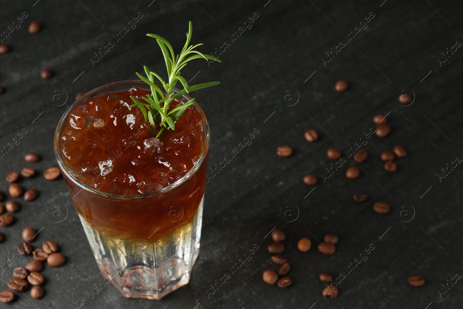 Photo of Refreshing espresso tonic drink with rosemary and coffee beans on dark table, closeup