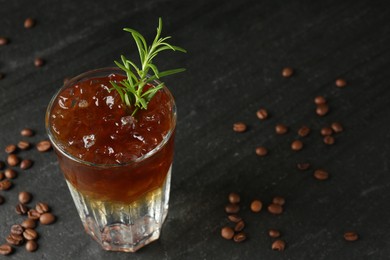 Photo of Refreshing espresso tonic drink with rosemary and coffee beans on dark table, closeup