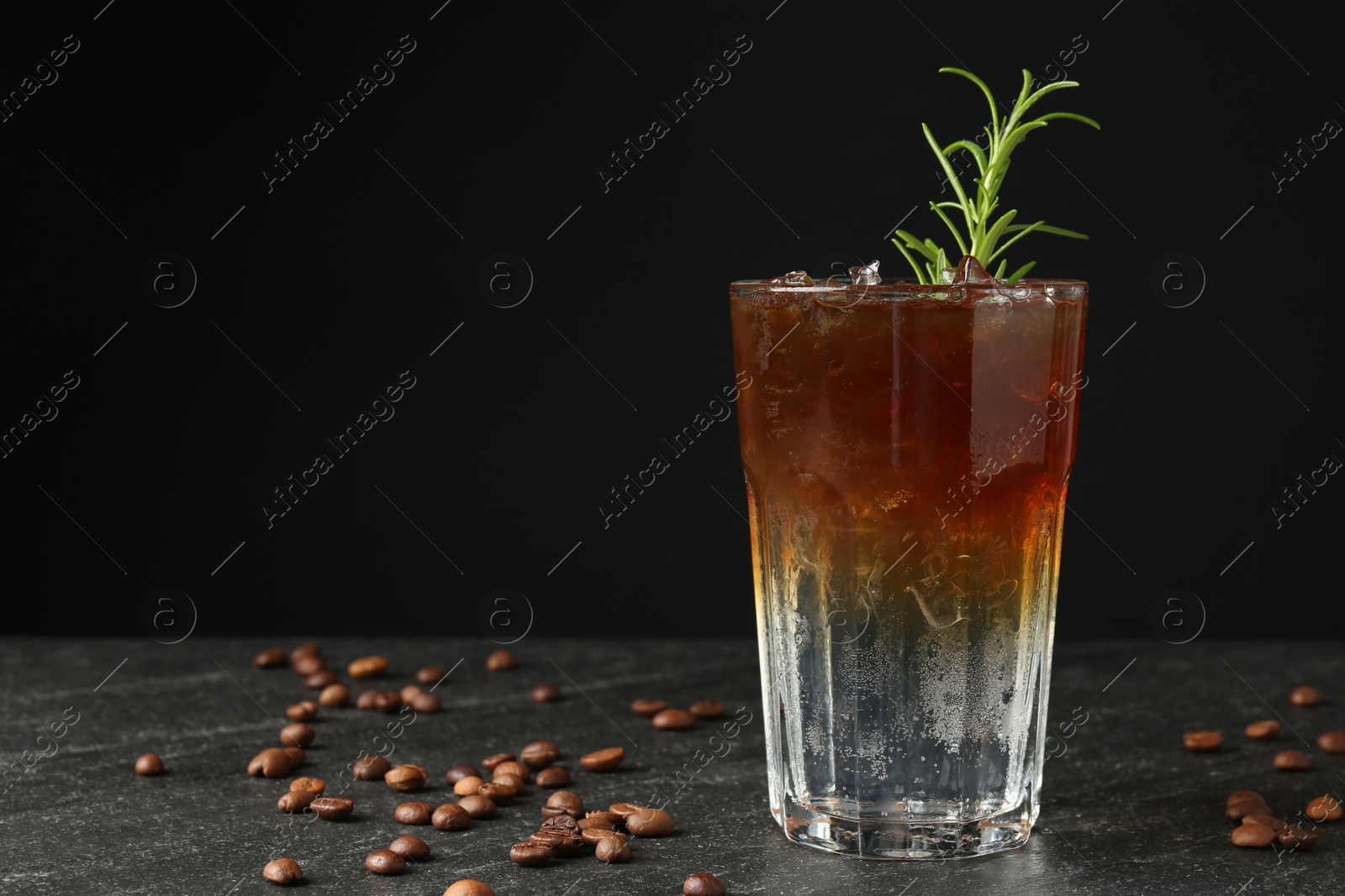 Photo of Refreshing espresso tonic drink with rosemary and coffee beans on dark table. Space for text