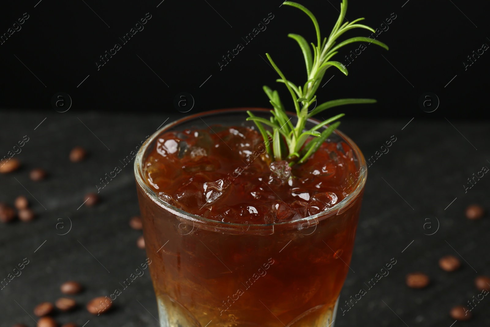 Photo of Refreshing espresso tonic drink with rosemary on dark background, closeup