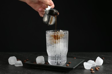 Woman making refreshing espresso tonic drink at dark table, closeup