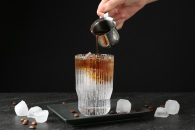 Woman making refreshing espresso tonic drink at dark table, closeup