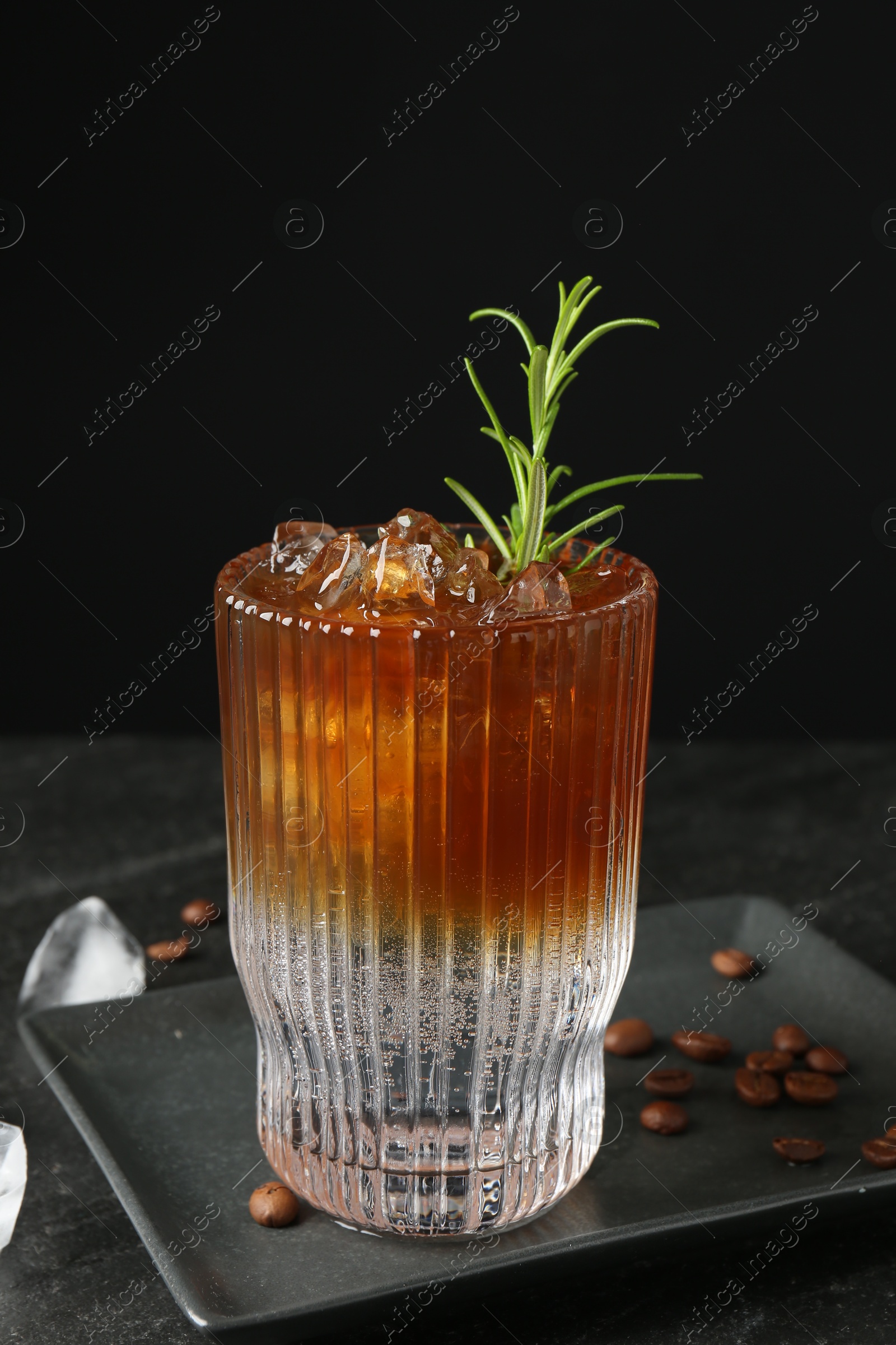 Photo of Refreshing espresso tonic drink with rosemary, ice and coffee beans on dark table