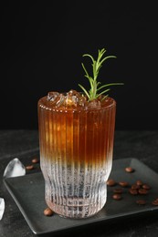 Refreshing espresso tonic drink with rosemary, ice and coffee beans on dark table