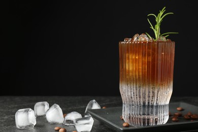 Photo of Refreshing espresso tonic drink with rosemary, ice and coffee beans on dark table. Space for text