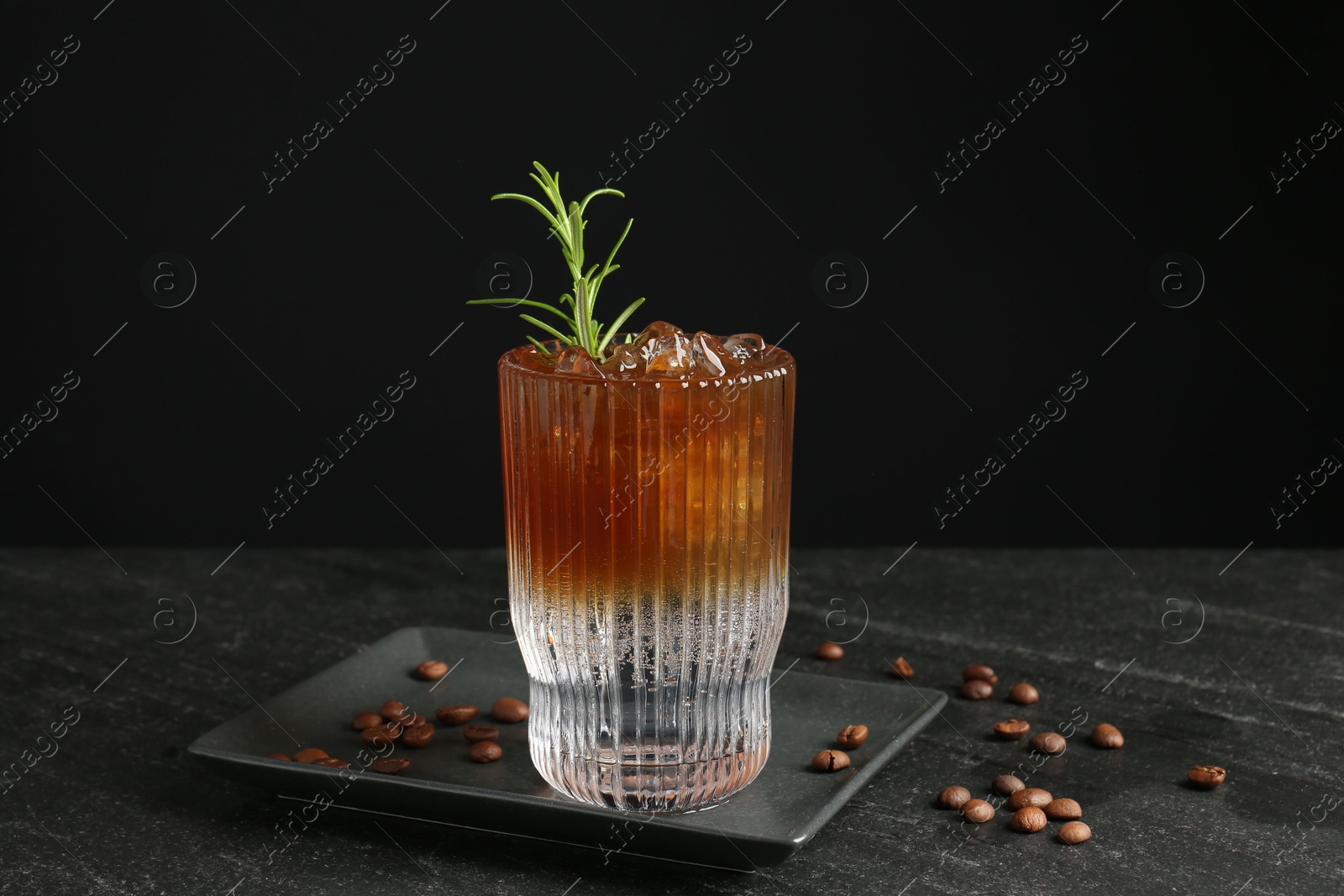 Photo of Refreshing espresso tonic drink with rosemary and coffee beans on dark table