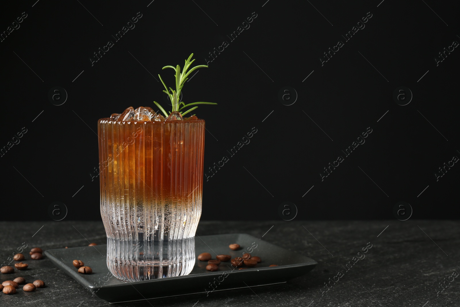 Photo of Refreshing espresso tonic drink with rosemary and coffee beans on dark table. Space for text