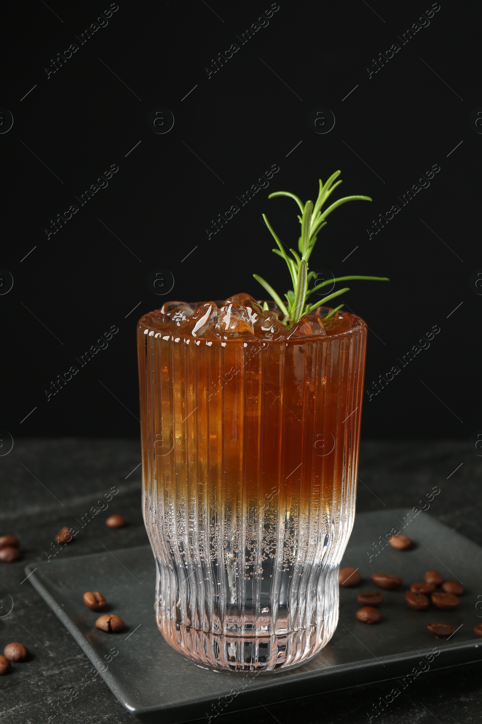 Photo of Refreshing espresso tonic drink with rosemary and coffee beans on dark table