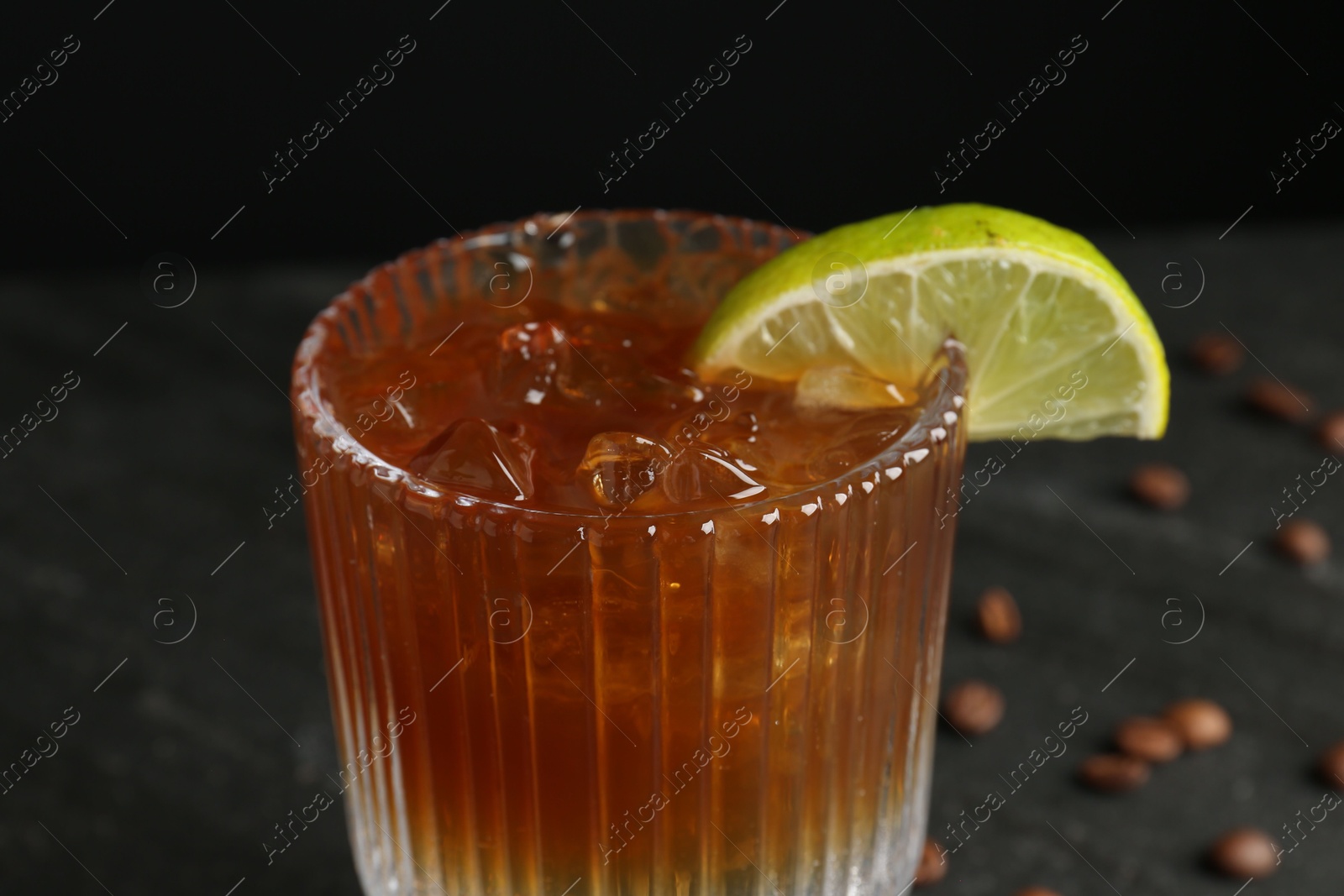 Photo of Refreshing espresso tonic drink with slice of lime on dark background, closeup