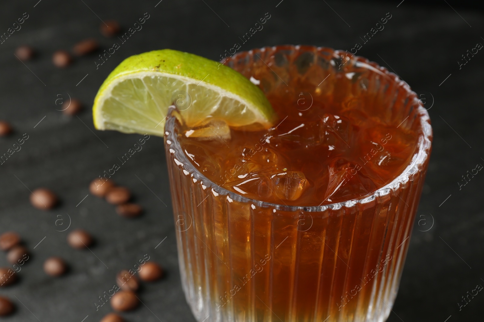 Photo of Refreshing espresso tonic drink with slice of lime on dark background, closeup