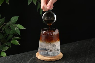 Woman making refreshing espresso tonic drink at dark table, closeup