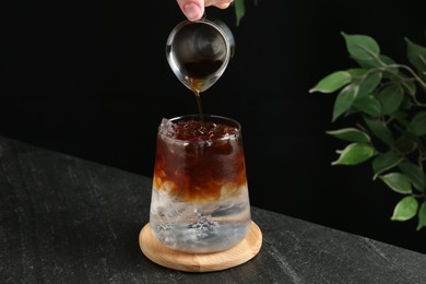 Woman making refreshing espresso tonic drink at dark table, closeup