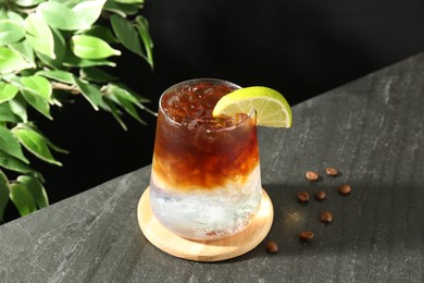 Photo of Refreshing espresso tonic drink with slice of lime and coffee beans on dark table