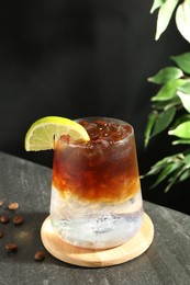 Photo of Refreshing espresso tonic drink with slice of lime and coffee beans on dark table