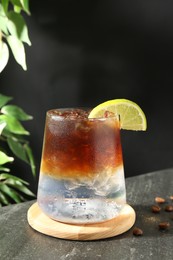 Photo of Refreshing espresso tonic drink with slice of lime and coffee beans on dark table