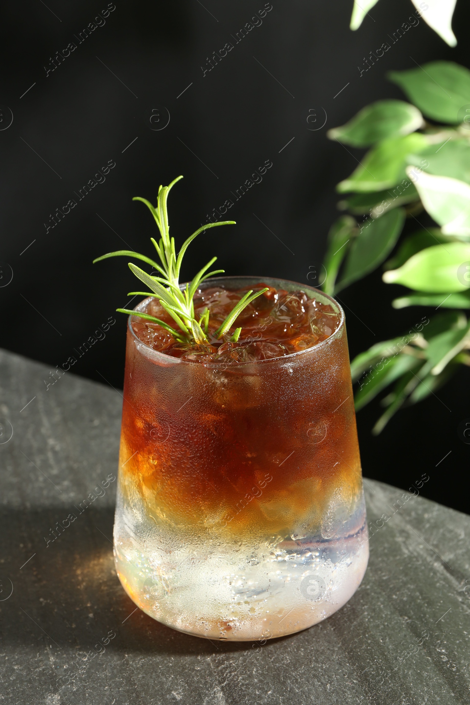 Photo of Refreshing espresso tonic drink with rosemary on dark table