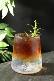 Photo of Refreshing espresso tonic drink with rosemary on dark table