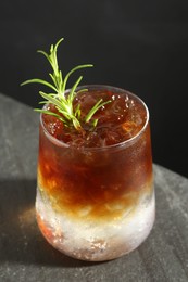 Photo of Refreshing espresso tonic drink with rosemary on dark table