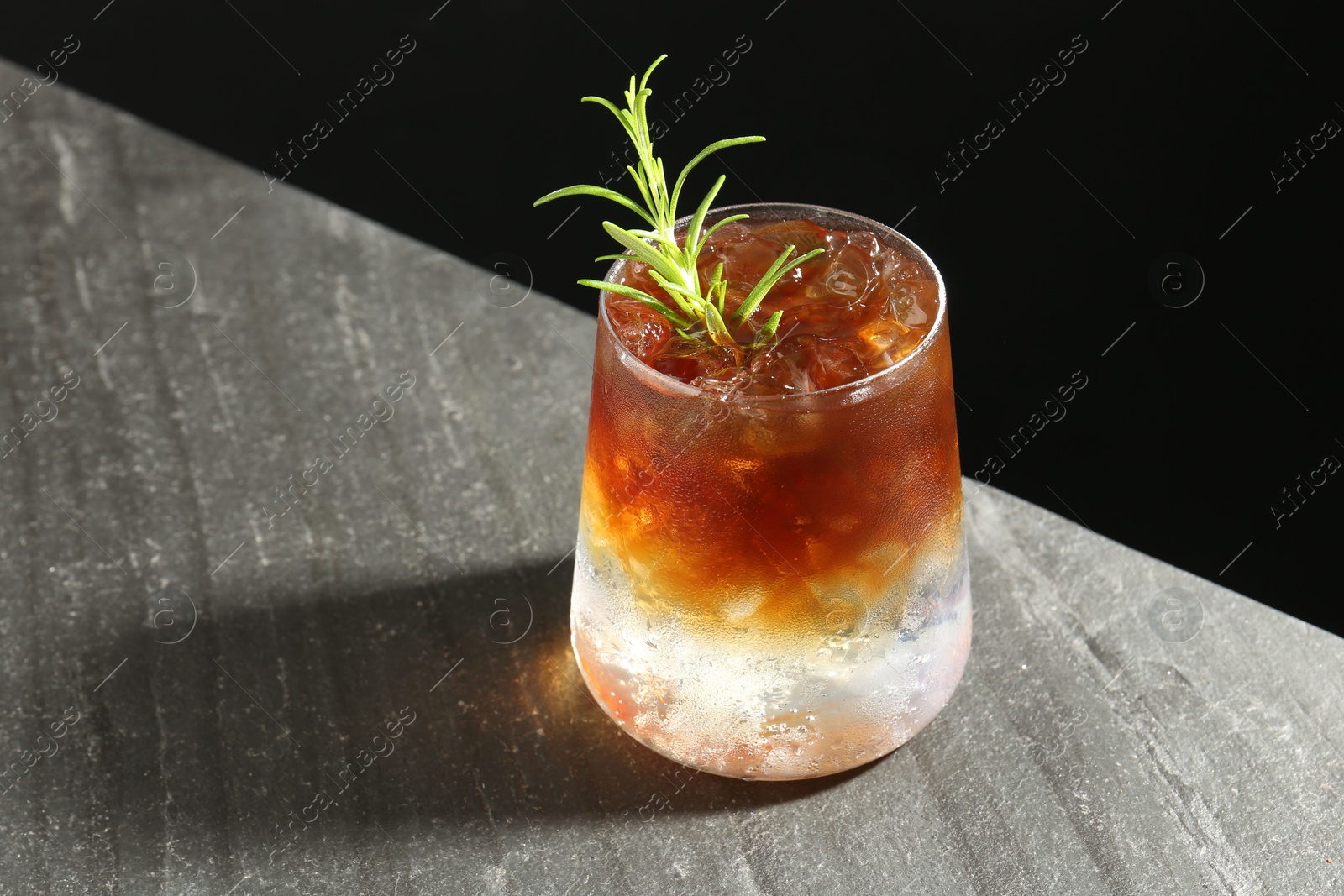 Photo of Refreshing espresso tonic drink with rosemary on dark table