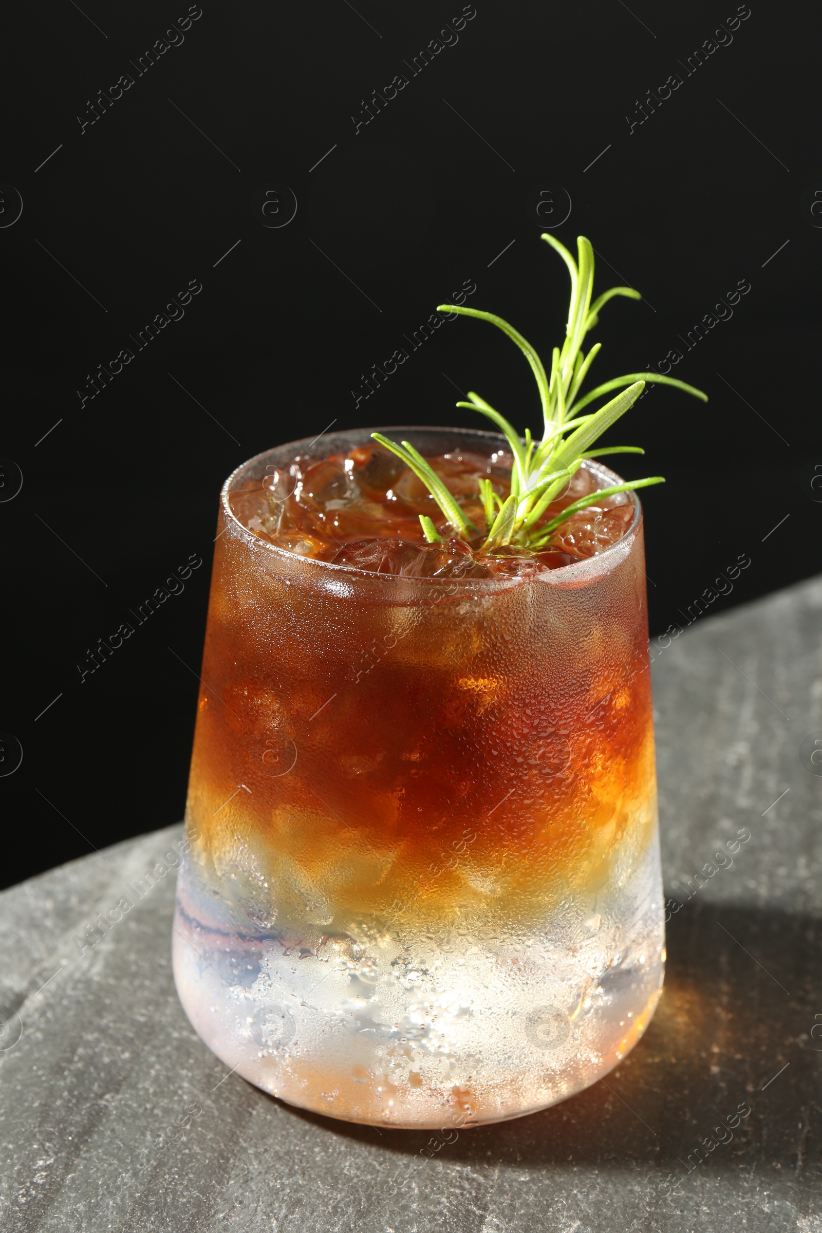 Photo of Refreshing espresso tonic drink with rosemary on dark table