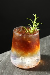 Photo of Refreshing espresso tonic drink with rosemary on dark table