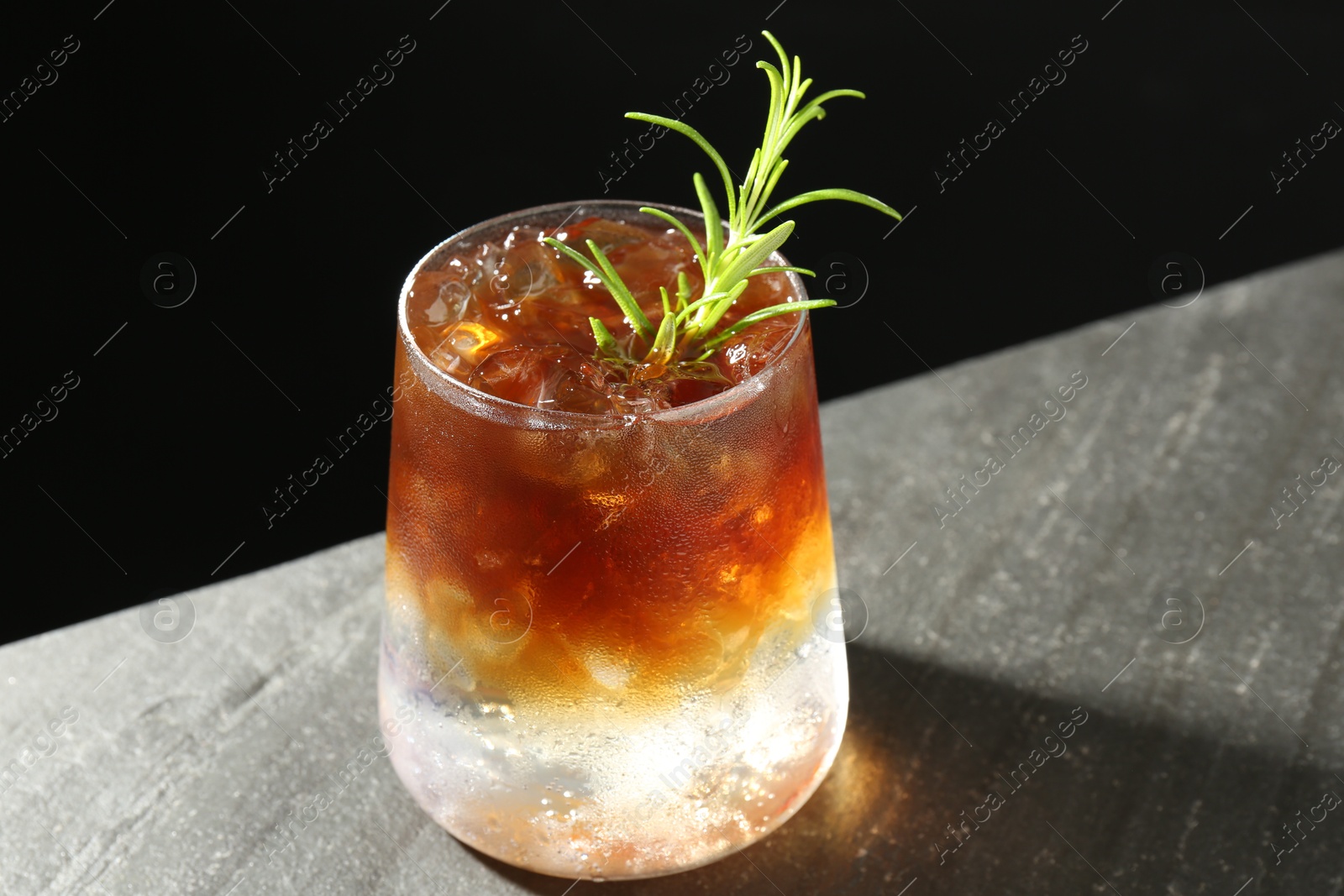 Photo of Refreshing espresso tonic drink with rosemary on dark table