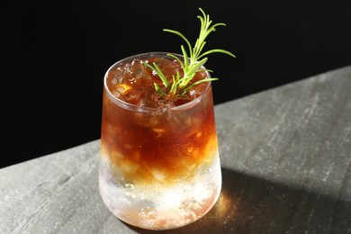 Refreshing espresso tonic drink with rosemary on dark table