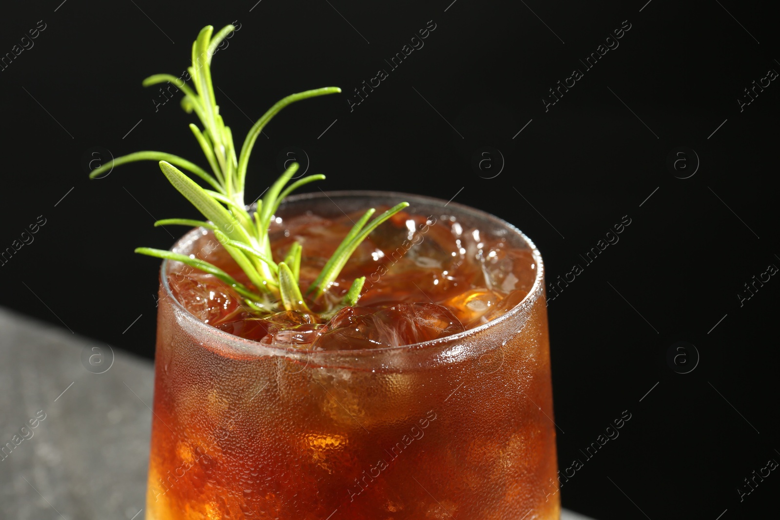 Photo of Refreshing espresso tonic drink with rosemary on dark background, closeup