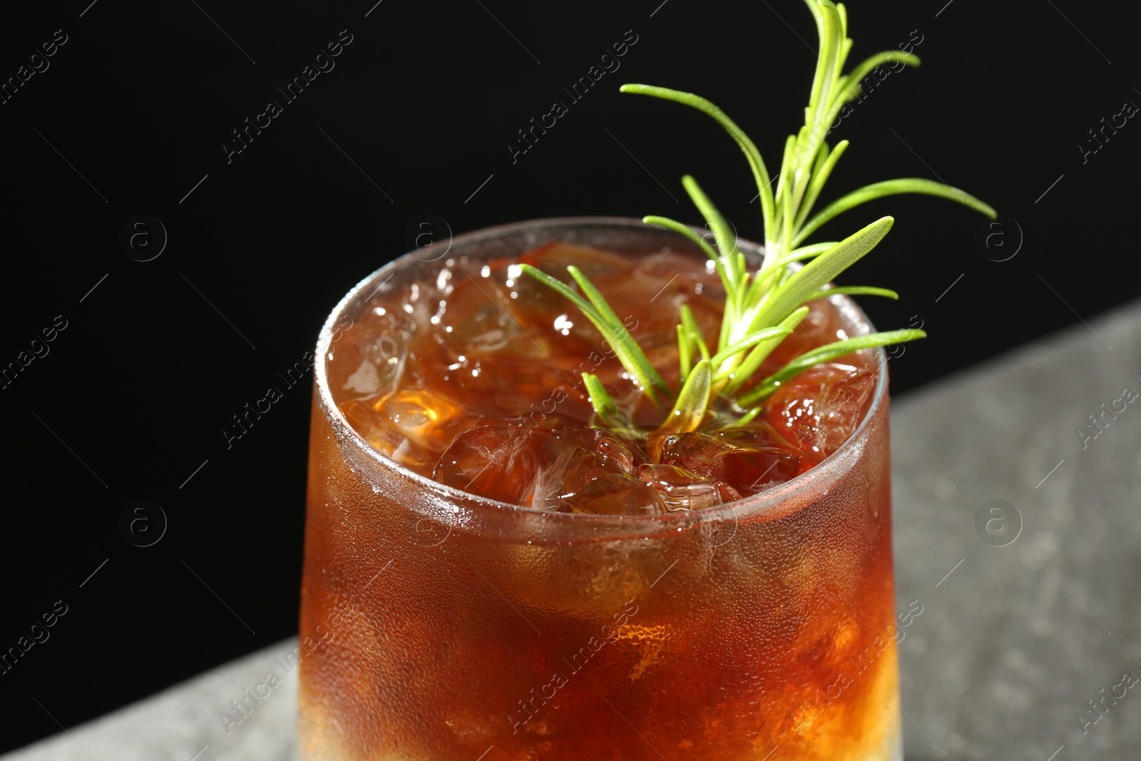 Photo of Refreshing espresso tonic drink with rosemary on dark background, closeup