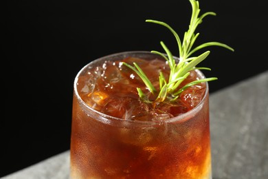 Photo of Refreshing espresso tonic drink with rosemary on dark background, closeup