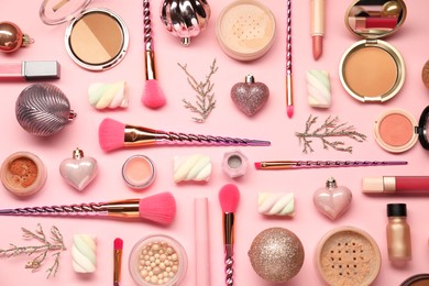 Photo of Different makeup brushes, decorative cosmetics and Christmas decor on pink background, flat lay